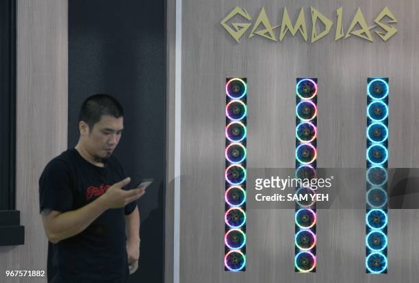 An visitor checks his smartphone next to a LED decorated fans during Computex 2018 at the Nangang Exhibition Center in Taipei on June 5, 2018.