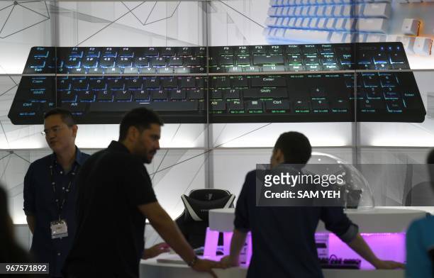 Visitors stand in front of a giant keyboard displayed on a screen during Computex 2018 at the Nangang Exhibition Center in Taipei on June 5, 2018.