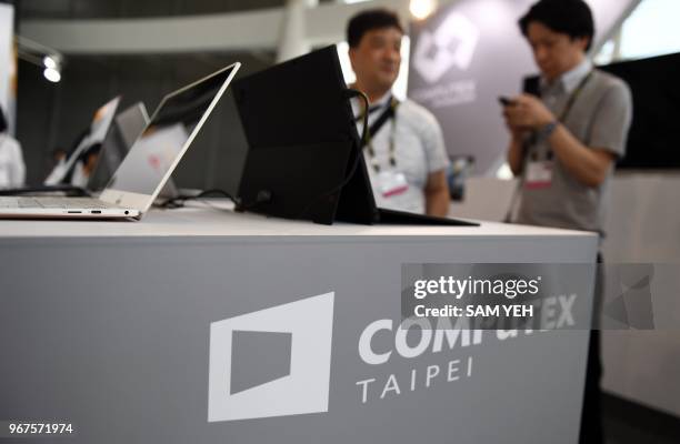 Two visitors stand behind a desk with Computex logo during Computex 2018 at the Nangang Exhibition Center in Taipei on June 5, 2018.