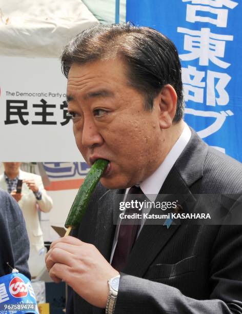 Japan's prime minister Yoshihiko Noda, right, tastes a cucumber which was produced in Fukushima prefecture damaged by the nuclear disaster that was...