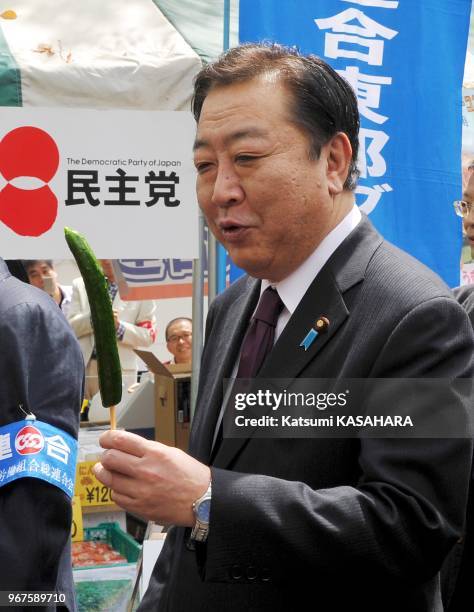 Japan's prime minister Yoshihiko Noda, right, tastes a cucumber which was produced in Fukushima prefecture damaged by the nuclear disaster that was...