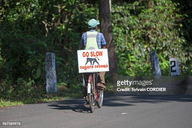 Inde,Tamil Nadu, montagnes de Annamalai , cycliste avec un panneau prévenant les automobilistes d'un passage eventuel de faune sauvage en l'occurence...