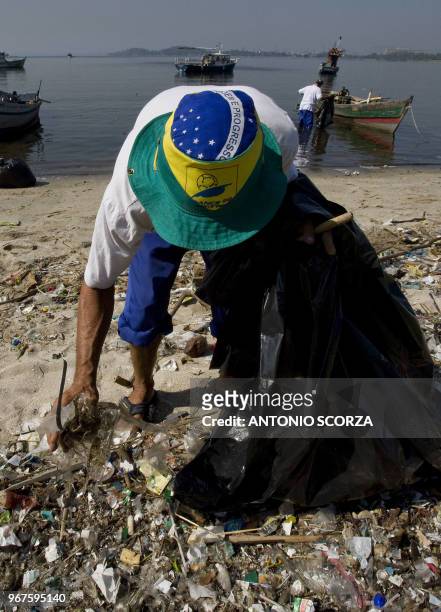 Brazilian fisherman 'Bira', wearing a hat with Brazil's national colors collects plastic garbage at Catalao Beach, inside the Guanabara bay, May 6 in...