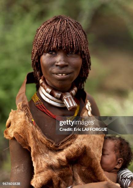 Hamar woman with her baby on October 26, 2008 in Omo valley, Ethiopia. This is a Hamar woman with a one week baby under her goat skin. This one is...