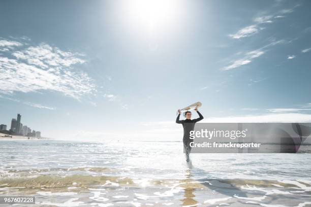 surfer walking in surfers paradise beach in australia - surfers paradise stock pictures, royalty-free photos & images