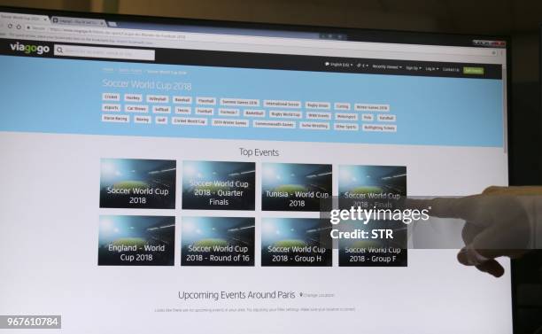 An illustration picture taken on June 5, 2018 in Paris shows a person pointing to a screen displaying the Viagogo website. - FIFA on June 5, 2018...