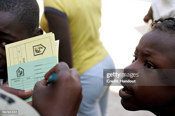 In this handout image provided by the United Nations Stabilization Mission in Haiti , A volunteer fills out vaccination cards for women and children...