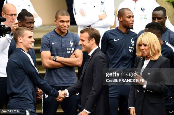 French President Emmanuel Macron speaks with France's forward Antoine Griezmann flanked by France's foward Kylian Mbappe and his wife Brigitte Macron...
