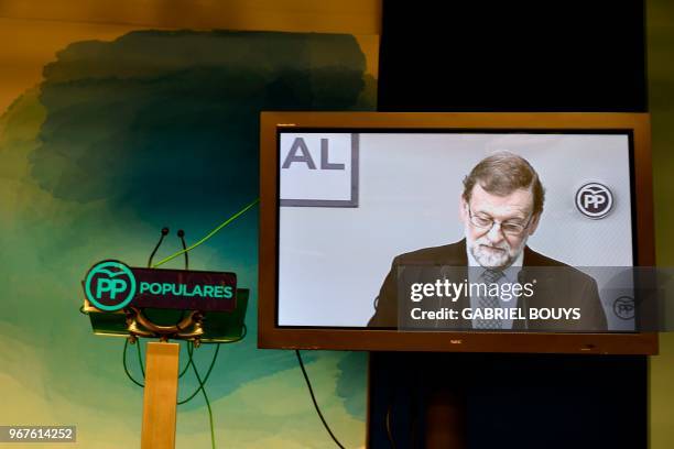 Former prime minister Mariano Rajoy is seen on a TV screen during a press conference following a People's Party meeting of the national executive...