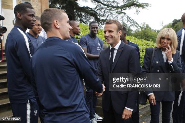French President Emmanuel Macron speaks with France's foward Antoine Griezmann flanked by his wife Brigitte Macron as they visit the team's training...