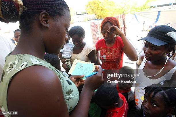 In this handout image provided by the United Nations Stabilization Mission in Haiti , A volunteer fills out vaccination cards for women and children...