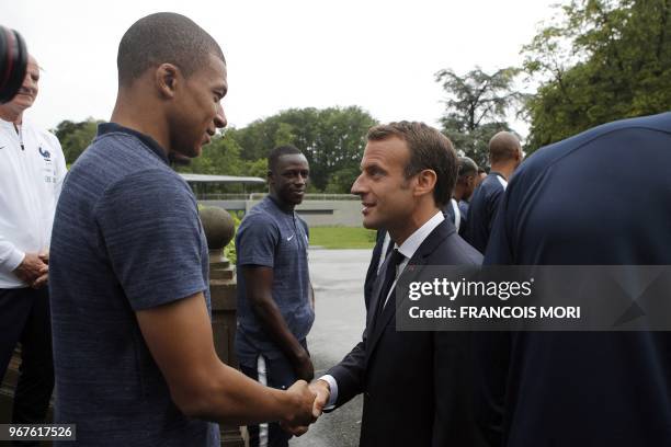 French President Emmanuel Macron shakes hands with France's foward Kylian Mbappe as he visits the team's training grounds in...