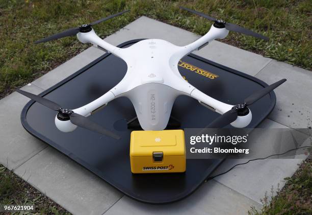 An M2 delivery drone, manufactured by Matternet Inc., sits on a landing pad next to a Swiss Post International Holding AG branded box containing...