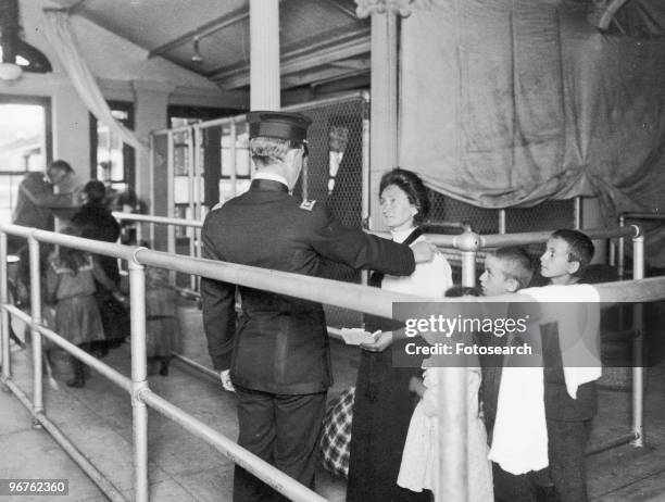 Photograph of an Immigration Officer Talking to a Female Immigrant with her Children on Ellis Island, New York circa 1880.