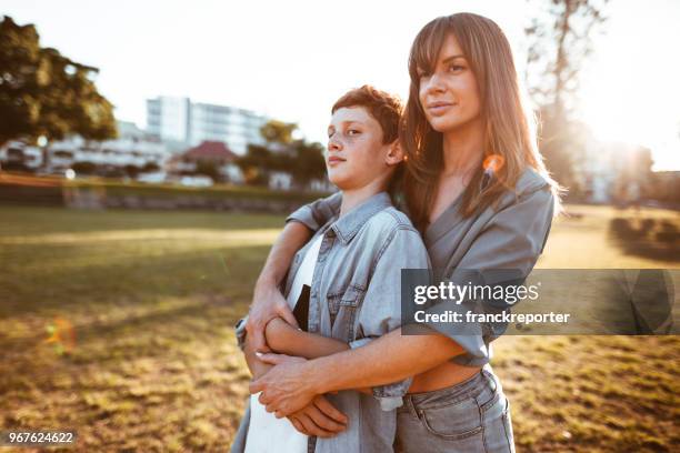 mom with arm around the son in the park - 13 year old cute boys stock pictures, royalty-free photos & images