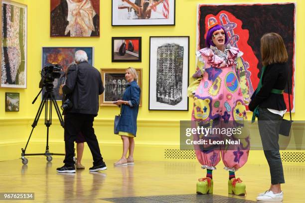 Picture depicting the fire-damaged Grenfell Tower, titled "Five Grand" by Luke Wade, is seen in the background as Artist Grayson Perry chats during a...