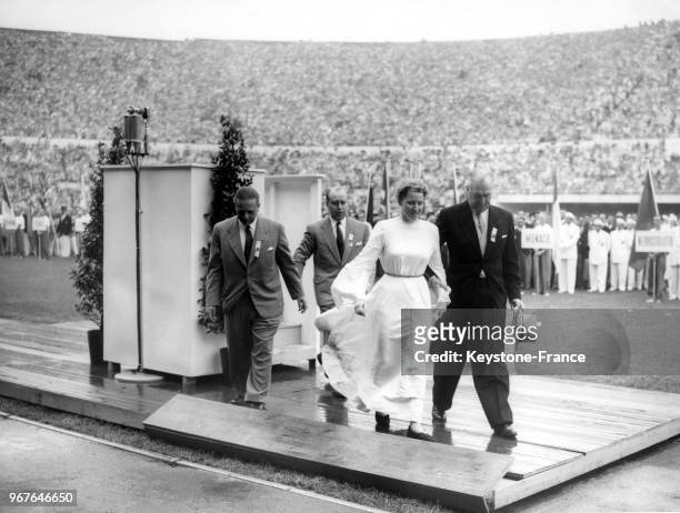 Barbara Rotraut Pleyer, jeune étudiante allemande vêtue d'une longue robe blanche, est escortée hors du stade par le président du comité olympique...