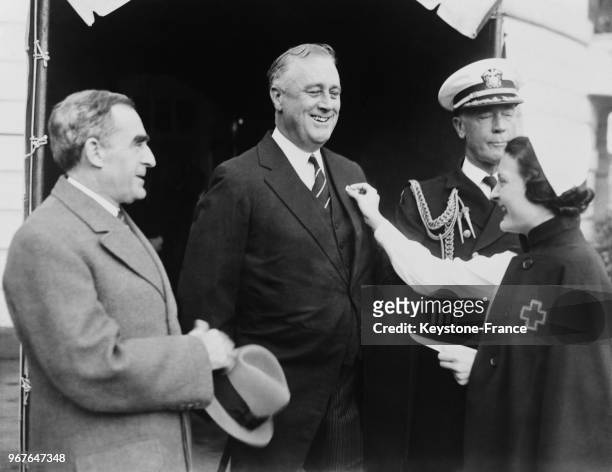 Le Président Roosevelt reçoit le petit insigne de la Croix Rouge après sa donation, à Washington DC, Etats-Unis le 22 novembre 1935.