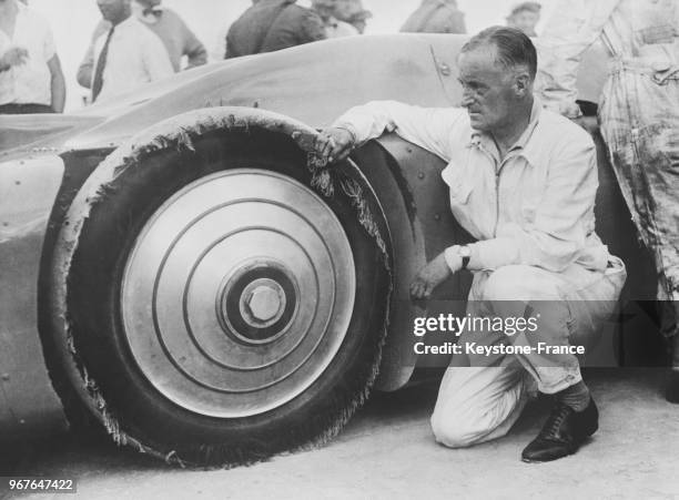 Le pilote automobile Malcolm Campbell qui a battu le record de vitesse en atteignant les 445 kms à l'heure, examine ses pneus dont l'enveloppe a été...