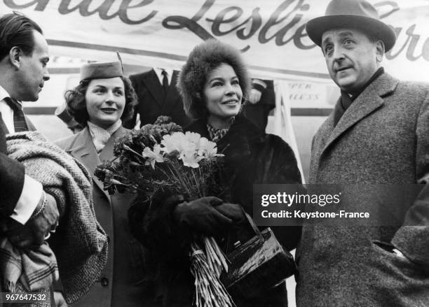 Leslie Caron est accueillie avec un bouquet de fleurs par le président de la MGM Beerman à son arrivée à Francfort, Allemagne le 18 décembre 1958.