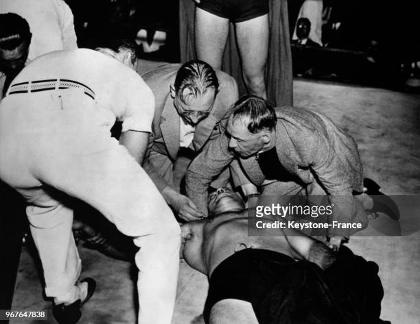 Des médecins et son entraîneur examinent le corps du boxeur Mike Romano, mort sur le ring lors d'un match contre Jack Donovan le 25 juin 1936 à...