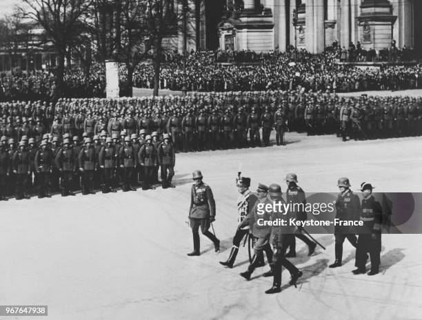 Hitler passent les troupes en revue, à sa droite le maréchal von Mackensen, à sa gauche le général von Fritsch et derrière le général Goering et...