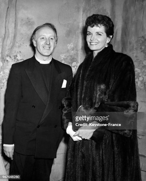 Actrice américaine Jane Russell, vêtue d'un manteau de fourrure, sourit aux côtés du révérend AWG Hudson lors de la première du film de Billy Graham...
