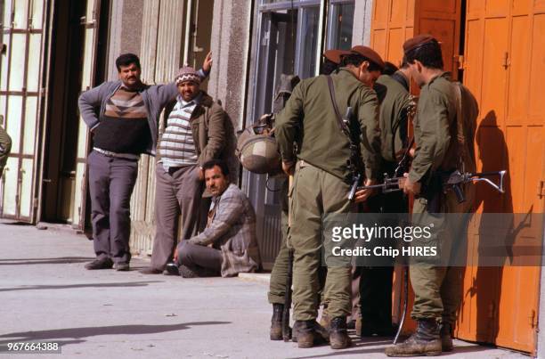 Palestiniens à côté de soldats de Tsahal lors de troubles le 19 janvier 1988 dans les Territoires Occupés en Israël.