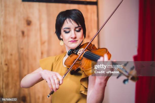 young and beautiful woman artist playing the violin on the stage. - soloist stock pictures, royalty-free photos & images