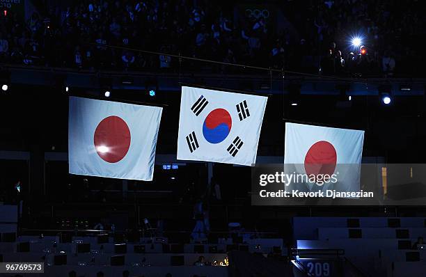 The flags of Japan and South Korea are raised during the playing of the National Anthem of South Korea at the medal ceremony for the Men's 500m Speed...