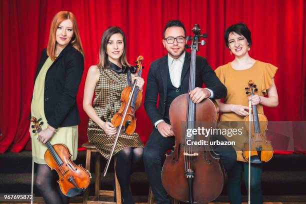 string quartet posing after the concert on stage. - classical orchestral music stock pictures, royalty-free photos & images