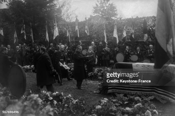 Monsieur Millerand, ancien président de la République jette l'eau bénite sur le cercueil dans le petit cimetière de Nubécourt, derrière lui Messieurs...