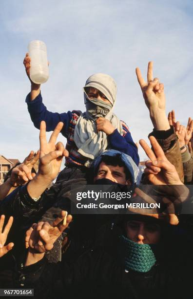 Un enfant, le visage masqué est porté par des manifestants faisant le V de la victoire, janvier 1990, Podujevo, Yougoslavie.