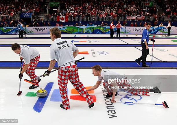 Haavard Vad Petersson of Norway releases his stone down the sheet as teammates Torger Nergaard and Christoffer Svae brush the ice during the men's...