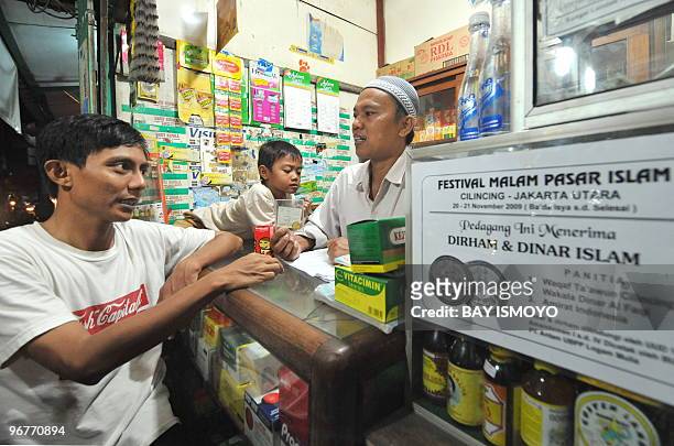 Photograph taken on January 27, 2010 shows Sabeni , an Indonesian pharmacist, attending to his shop posted with a notice the shop is accepting gold...