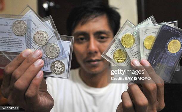 Photograph taken on January 27, 2010 shows Sofyan, an Indonesian moneychanger displaying silver dirham and gold dinar coins used in the daily...