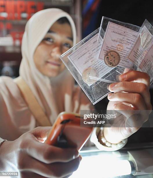 Photograph taken on January 27, 2010 shows an Indonesian trader selling credit load for mobile phones displaying dirham silver coins used in the...