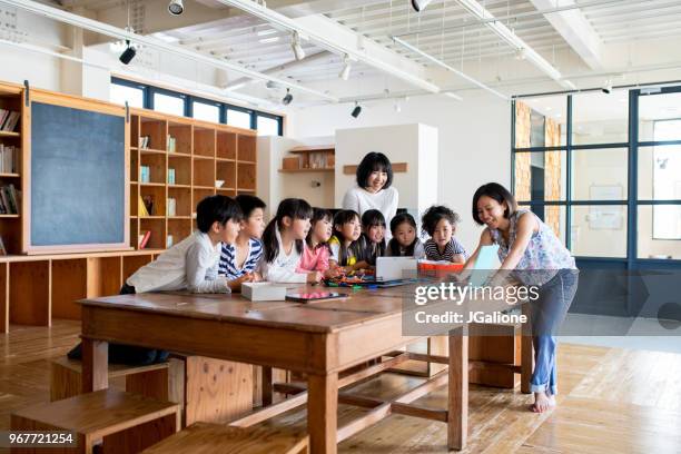 läraren förklarar ett projekt till en grupp av unga studenter - japanese elementary school bildbanksfoton och bilder