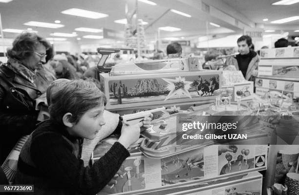 Enfant s'entrainant au tir avec un jeu dans un Grand Magasin avnt Noël le 26 novembre 1975 à Paris, France.