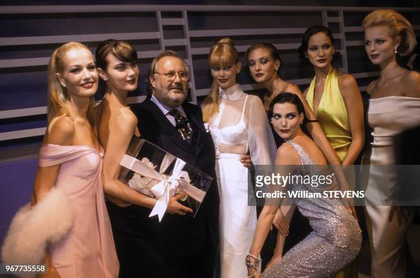 Portrait du couturier Gianco Ferré entouré de ses mannequins après un défilé le 14 octobre 1995 à Paris, France.