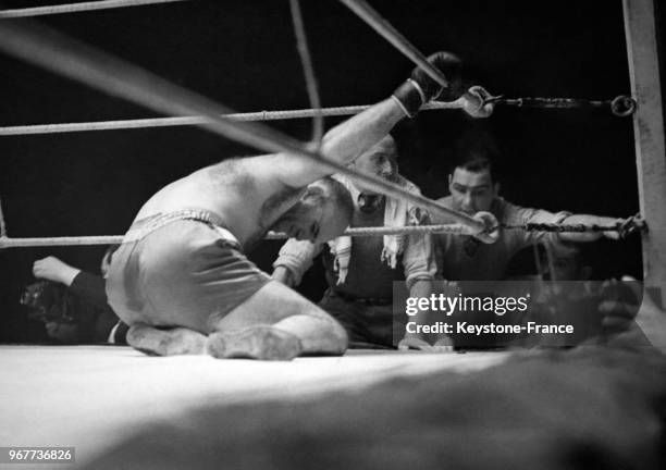 Le boxeur français Marcel Thil se tord de douleur sur le ring sous le regard inquiet de son entraîneur, après un coup bas porté par son adversaire...