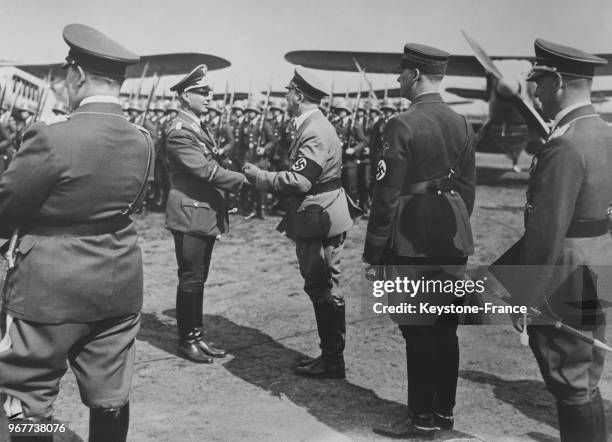 Devant les avions militaires offerts au Chancelier, une compagnie d'honneur de la Reichswehr rend les honneurs et le führer serre la main du...