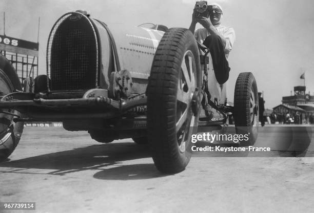 Le coureur automobile Benoist au volant de la Bugatti filme les spectateurs sur l'autodrome de Linas-Monthléry, en France le 23 juin 1935.