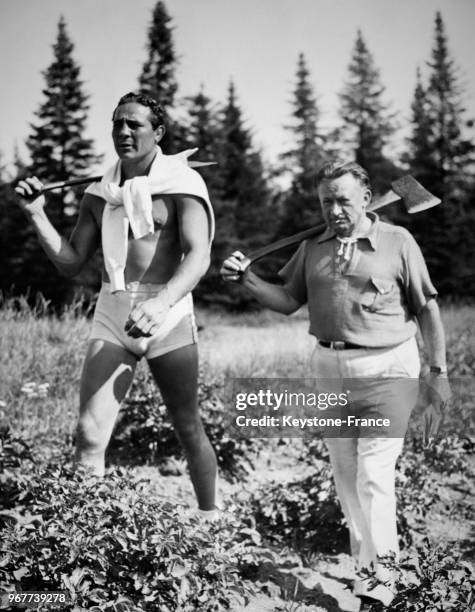 Le boxeur Max Baer se remet en forme avec l'aide de son entraîneur Ancil Hoffman lors de marches en forêt avec des haches le 17 septembre 1935 aux...