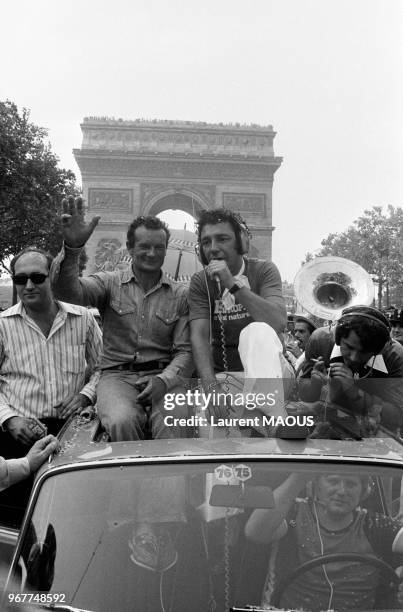 Le navigateur Eric Tabarly descend les Champs-Elyées assis sur le toit d'une voiture, avec à droite l'animateur d'Europe 1 Hubert, après sa victoire...