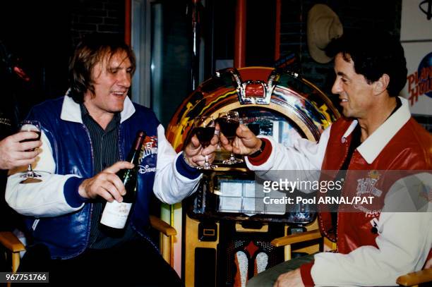 Les acteurs Gérard Depardieu et Sylvester Stalone trinquent avec une bouteille de vin de la cuvée Tigné appartenant à Depardieu lors de...