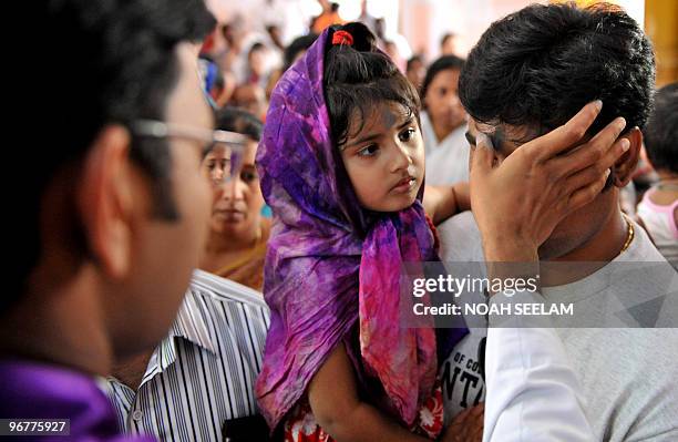 An Indian Catholic priest marks a symbol of the cross on the forehead of a Christian during an Ash Wednesday service at Saint Mary's Church in...