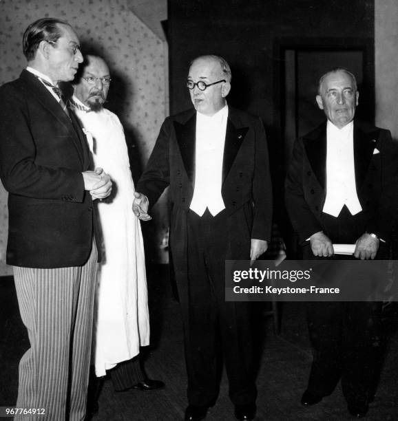 Le comédien Louis Jouvet est félicité par le président de la République Française Vincent Auriol en présence de l'auteur Jules Romains après la...