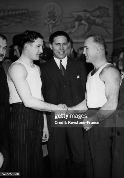 Poignée de mains entre les boxeurs Marcel Thil et Jack Mac Avoy qui doivent se rencontrer au Palais des Sports sous l'oeil de l'organisateur du...