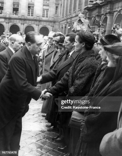 Le chef du Cabinet de la présidence de la république Henri Friol serre la main à Eve Curie et à Frédéric Joliot-Curie, soeur et époux de la...